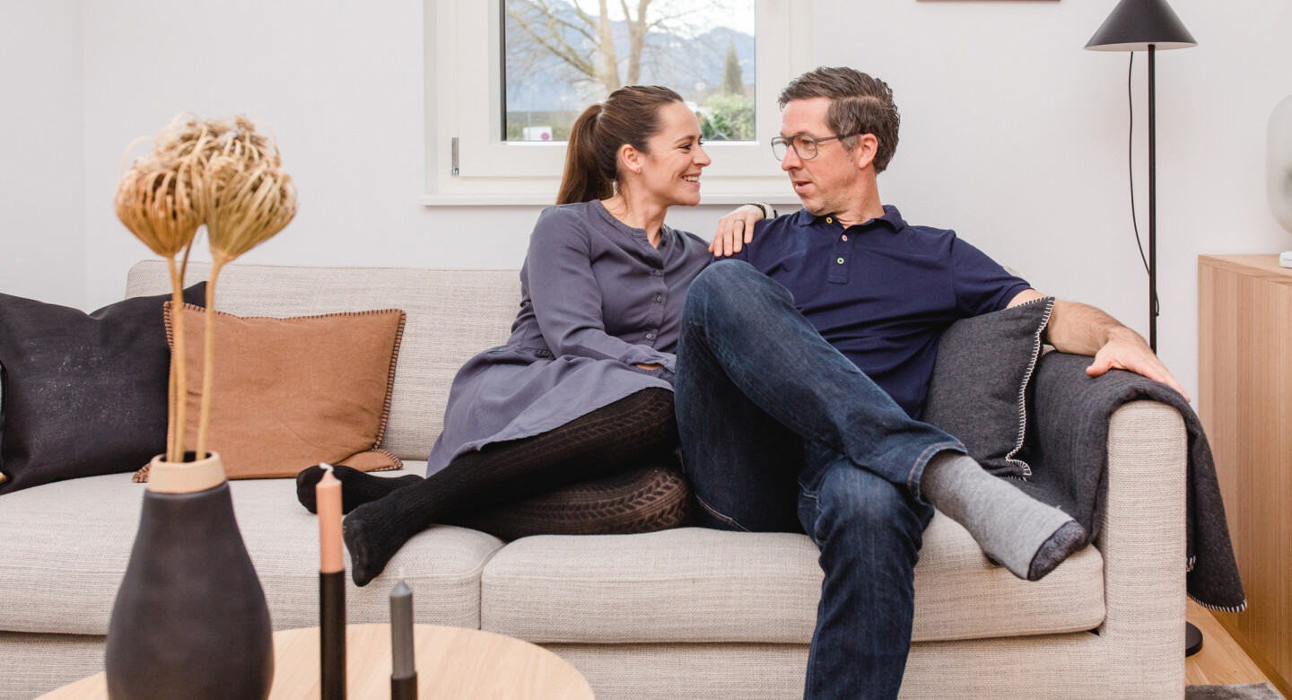 Frau sitzt mit Mann auf der Couch und unterhält sich David