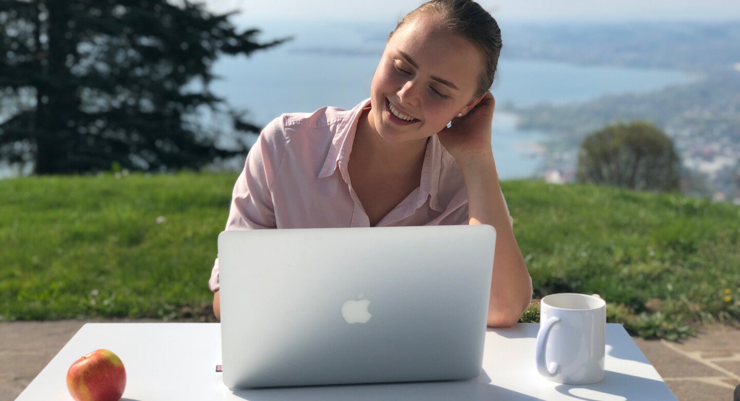 Rossmähder Person sitzt vor Laptop mit See im Hintergrund Rossmähder Person sitzt vor Laptop mit See im Hintergrund