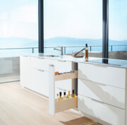 Offene und gefüllte Schublade in Arbeitsfläche, dahinter unscharfes Bergpanorama