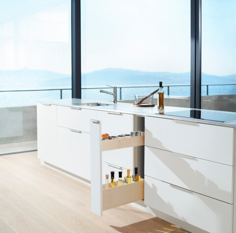 Offene und gefüllte Schublade in Arbeitsfläche, dahinter unscharfes Bergpanorama