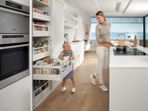 Frau mit Mädchen in Küche, Mädchen öffnet Schublade und Frau kocht David