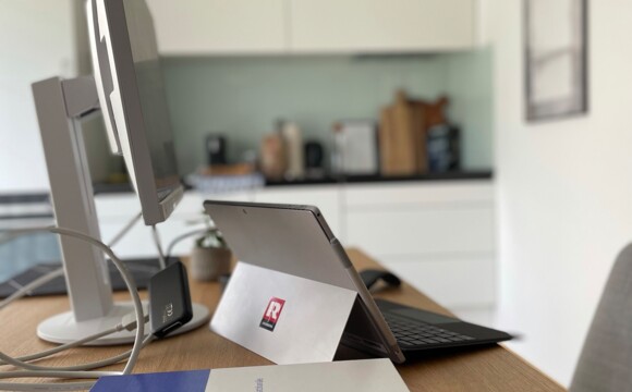 Schreibtisch mit Büroutensilien und Küche im Hintergrund David