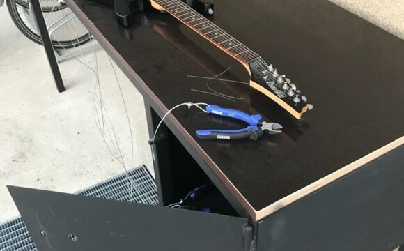 Gitarre auf schwarzem Tisch neben Zange